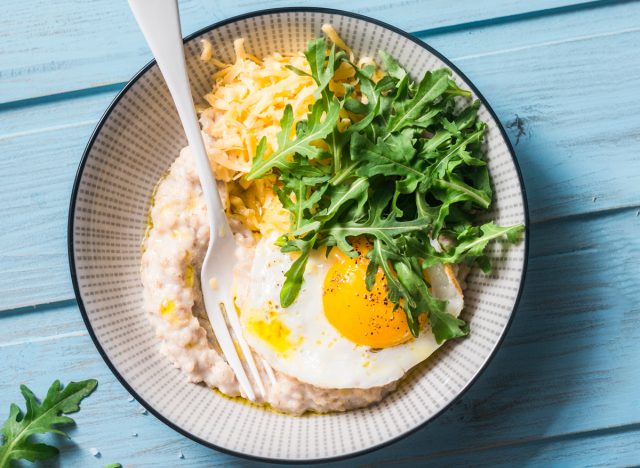 bowl of savory oatmeal with a sunny side up egg and arugula