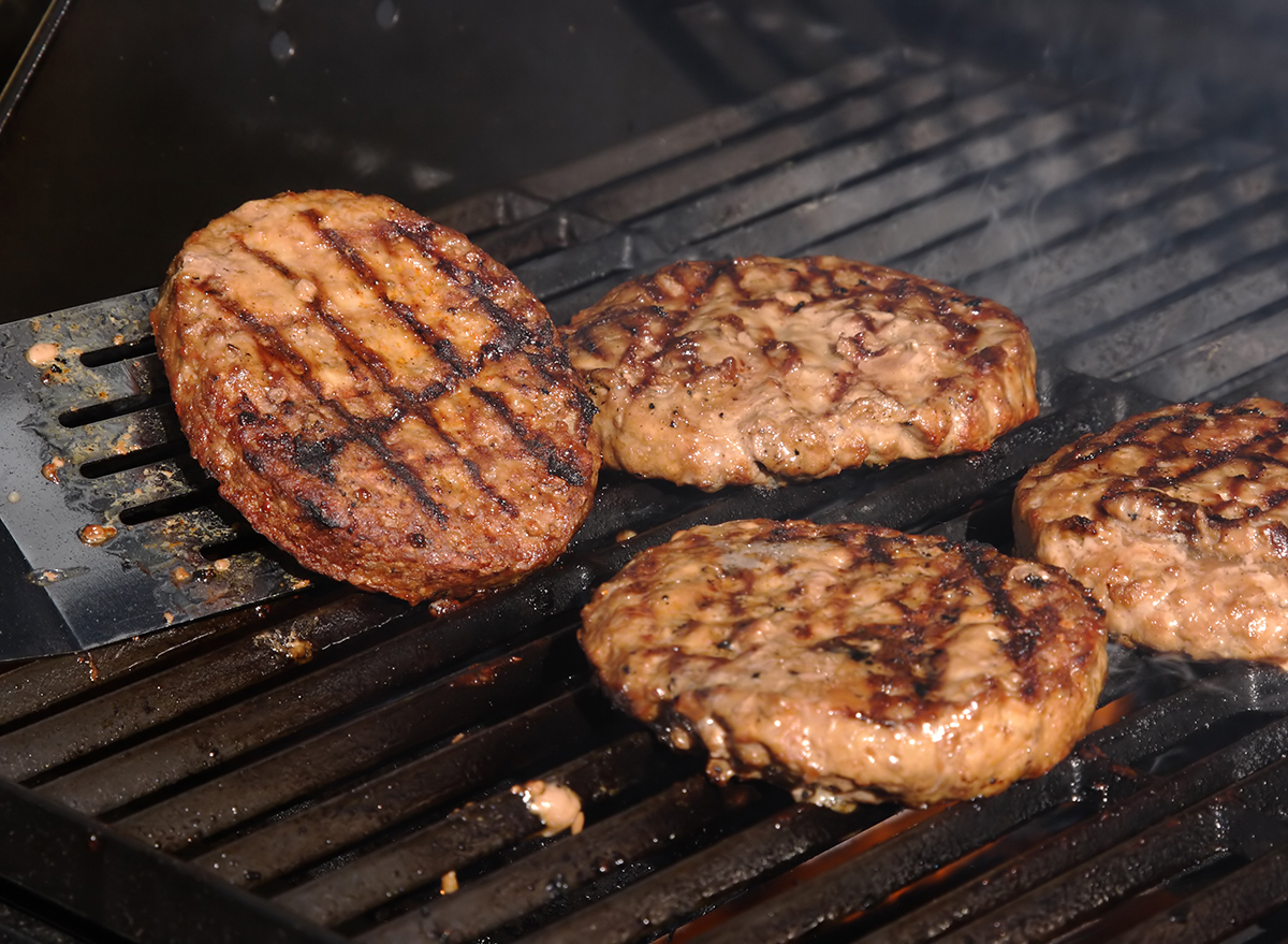 spatula flipping burger patty on open grill