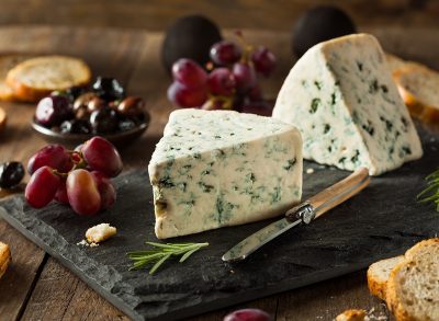 blue cheese on cheese board with crostinis and purple grapes