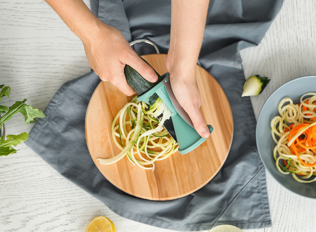 https://www.eatthis.com/wp-content/uploads/sites/4/2019/06/woman-spiralizing-zucchini-on-a-counter-with-other-spiralized-vegetables-shutterstock.jpg?quality=82&strip=1