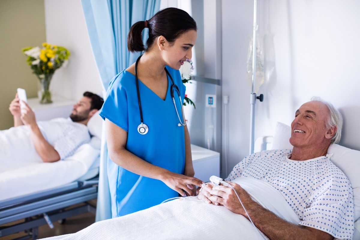 Male doctor examining female senior patient in the ward at hospital