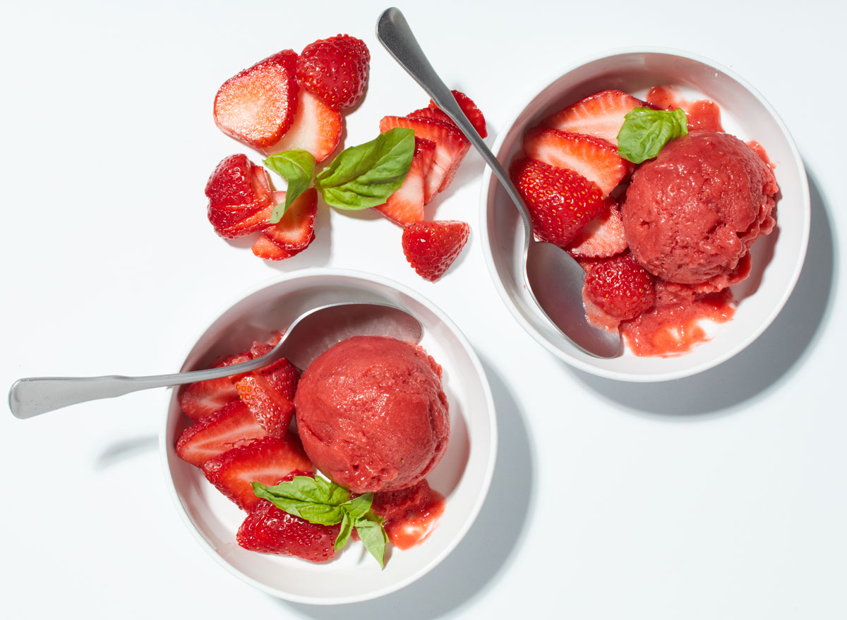 strawberry rhubarb ice with fresh strawberries and basil on a white table