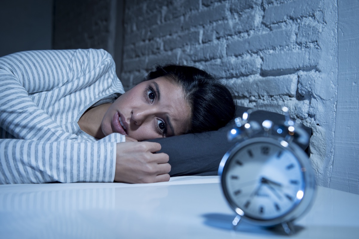 Spanish woman in house sleeps late in bed and tries to sleep, sleep insomnia or is afraid of nightmares that look sad and worried