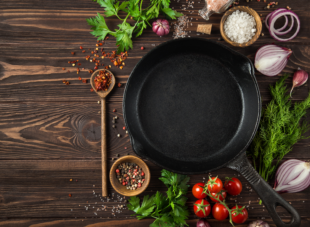 cast iron skillet with vegetables, herbs, and spices