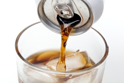 Brown soda in a clear glass against a white background