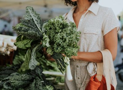 woman holding a bundle of two different types of kale