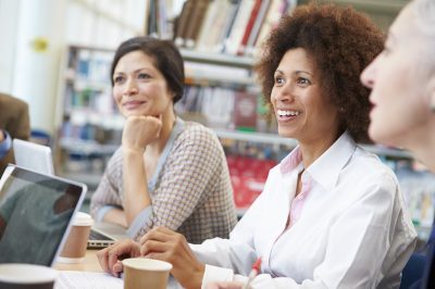 Group Of Mature Students Collaborating On Project In Library