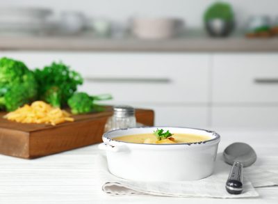 broccoli cheese soup in a bowl with sides of extra broccoli and cheese in the kitchen