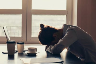 woman lying her head down on a desk