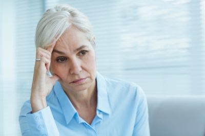 Sad senior woman looking away at home