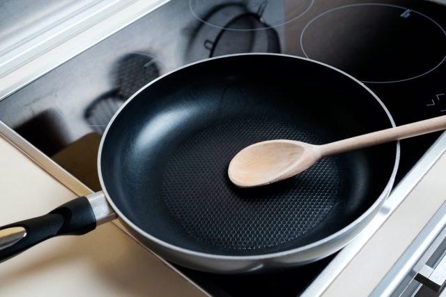 Dripping pan, wood spoon and black induction cooker