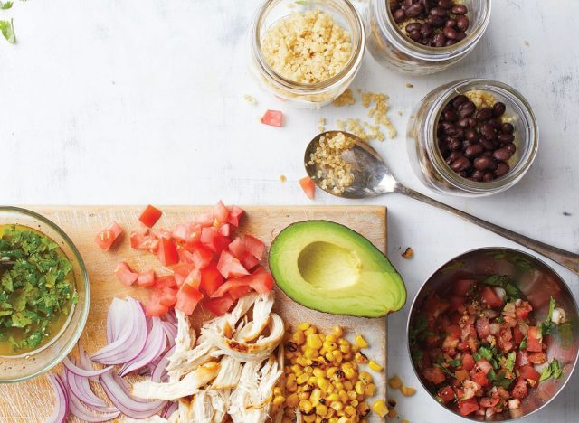 mexican quinoa and chicken salad on wooden cutting board with bowl of salsa