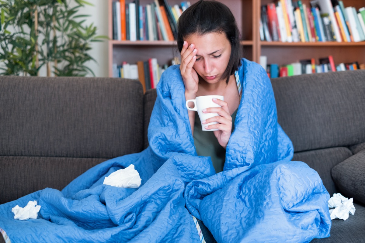woman covered with a blanket on the couch with high fever and flu