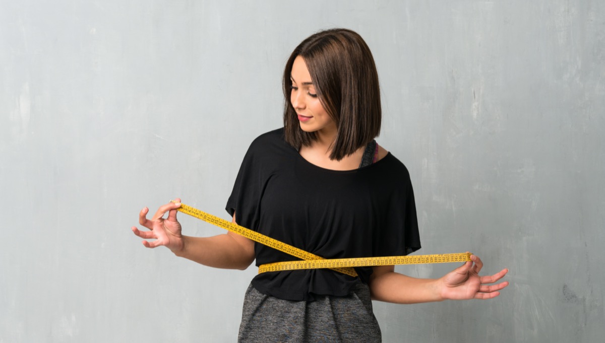 Young sporty woman with tape measure