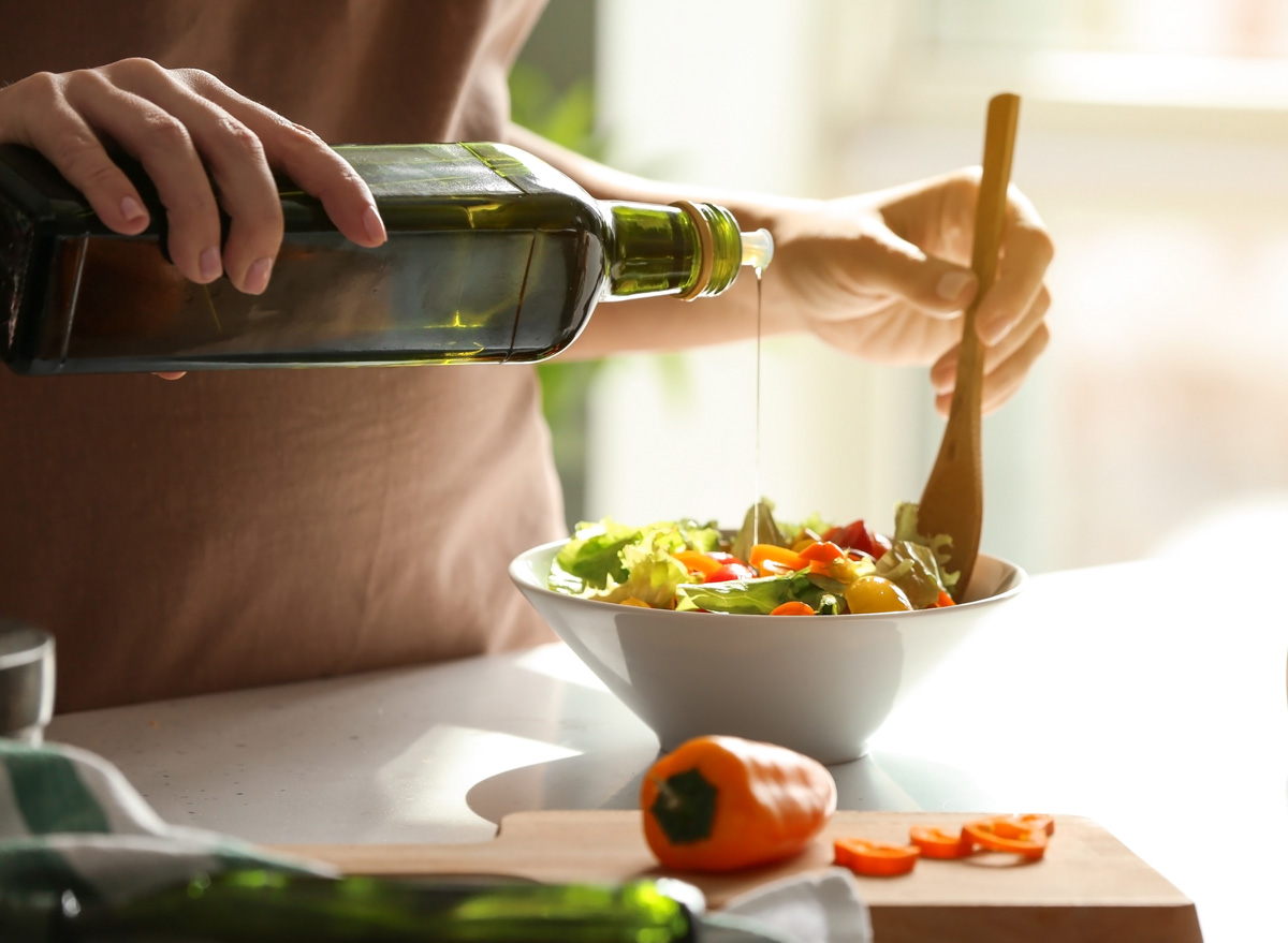 Is Olive Oil Good for You - pouring extra virgin olive oil on a veggie salad