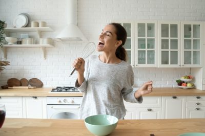 Happy woman singing in her kitchen