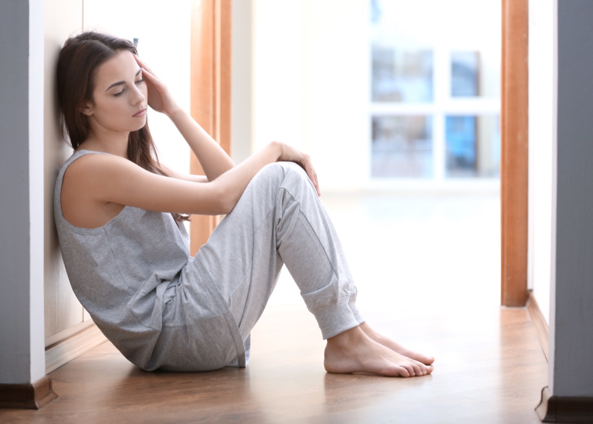 Depressed young woman sitting on the floor at home