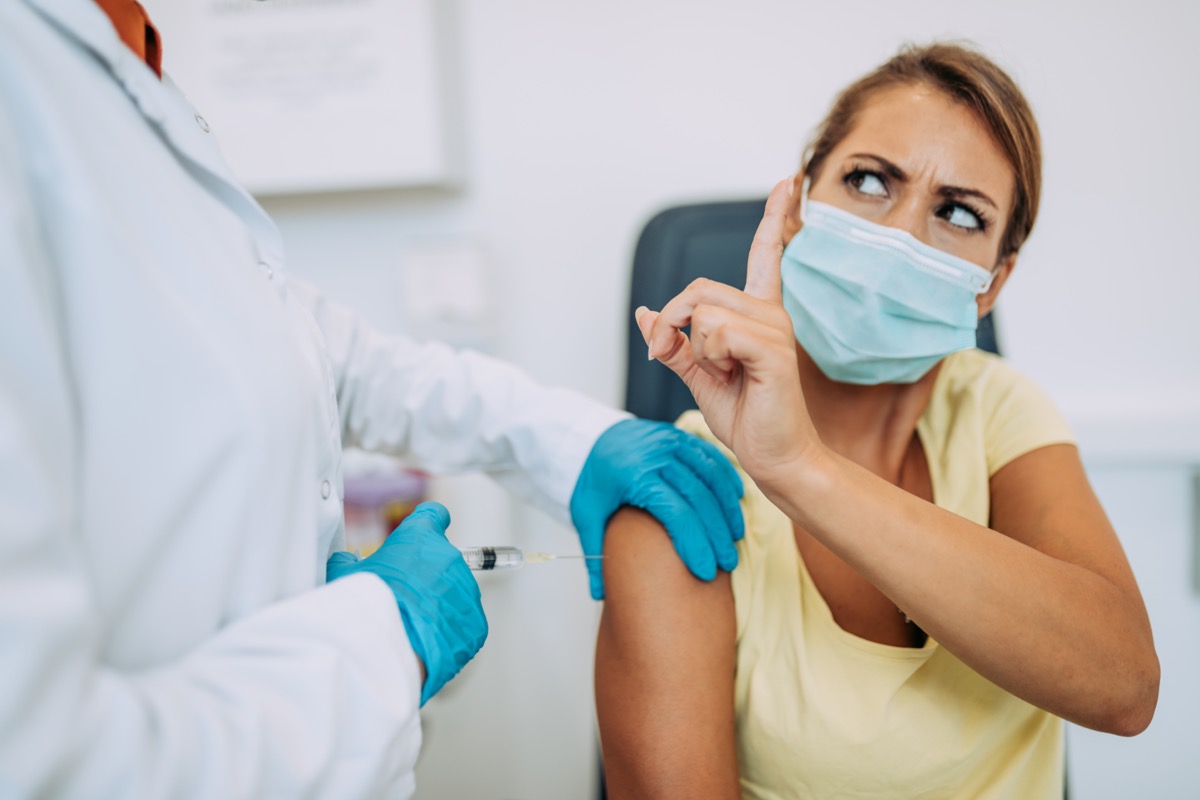 Woman doctor or nurse trying to give virus injection or vaccine to scared patient.