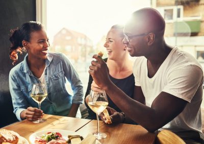 group of multiethnic friends in their 30s drinking wine outside at a table