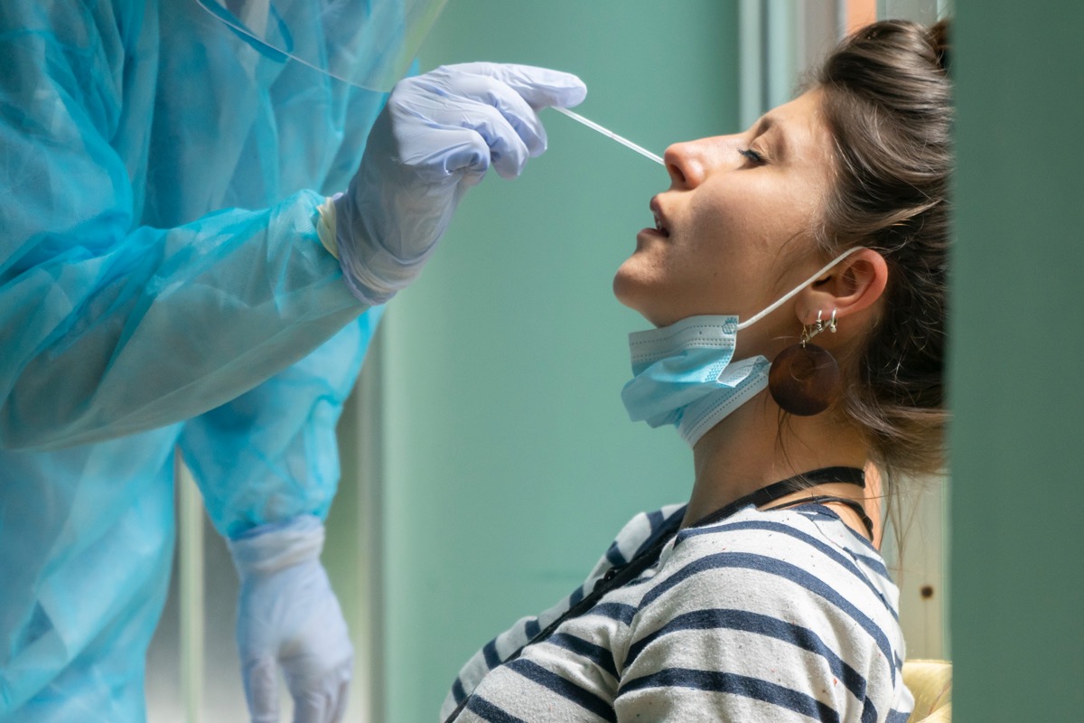 Healthcare worker with protective equipment performs coronavirus swab on a woman.