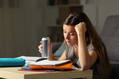 young woman drinking energy drink while studying