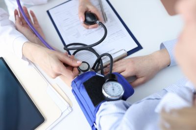 doctor measuring a patient's blood pressure with blood pressure cuff