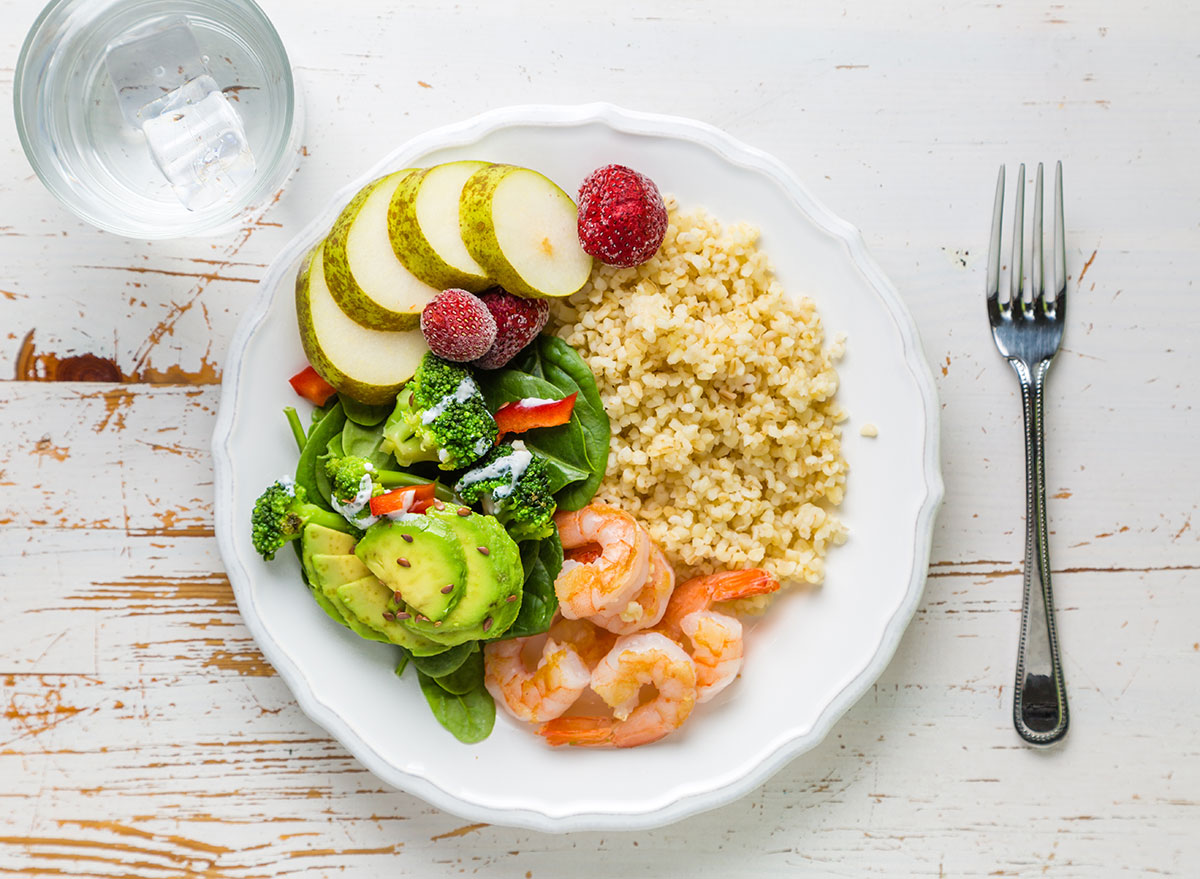  A plate of balanced meal with pears, strawberries, broccoli, avocado, bulgur, and shrimps.