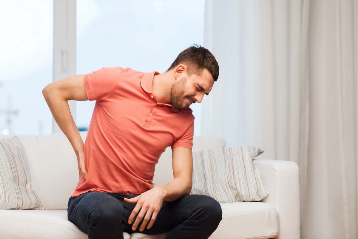 young man sitting on sofa with kidney pain