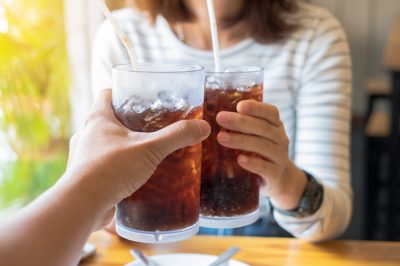 two people toasting with glasses of soda