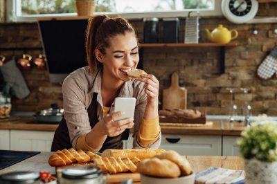 woman eating bread while text messaging