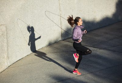 Fitness woman skipping with a jump rope outdoors. Female doing fitness training in morning.