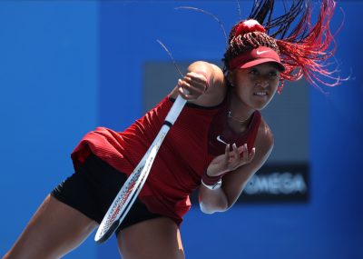 naomi osaka serving a tennis ball and holding tennis racket