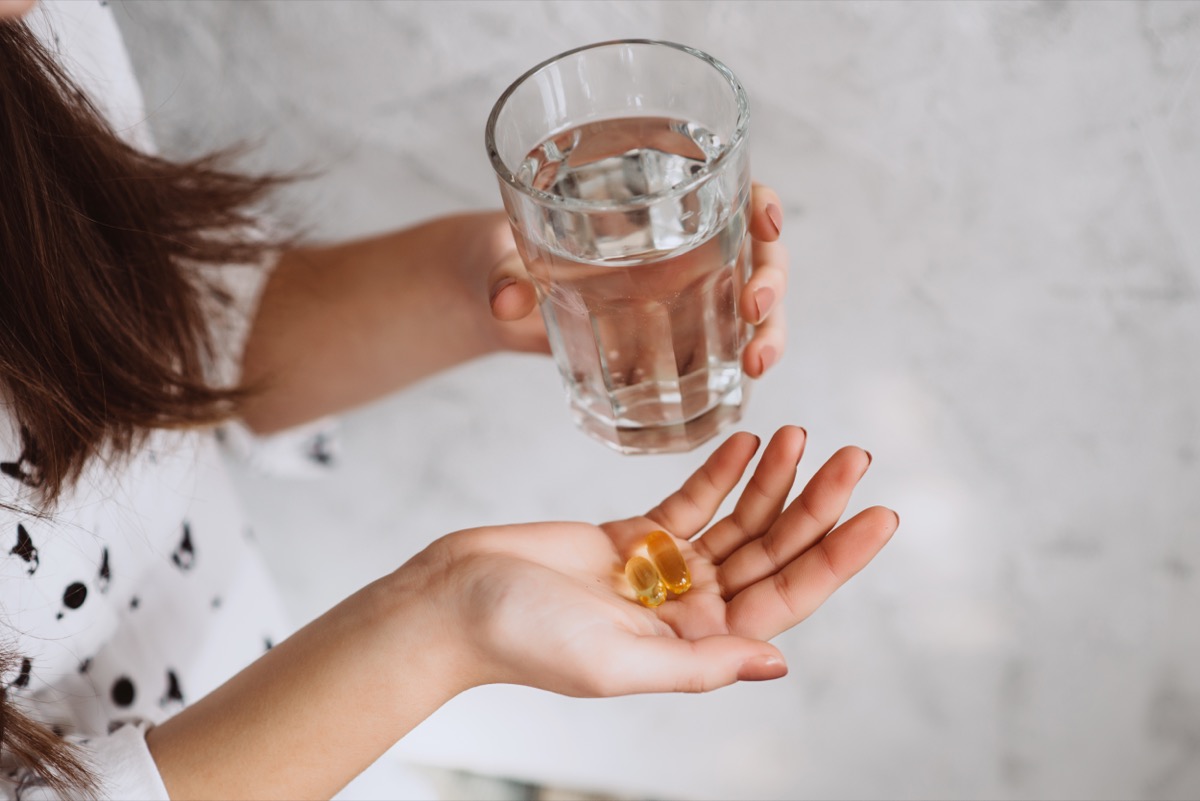 Women taking vitamin D supplements with water