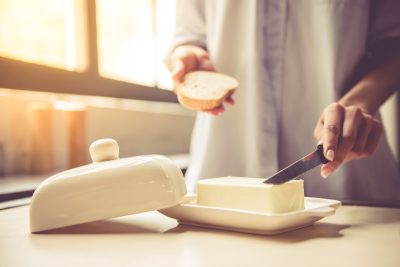 woman buttering a piece of toast in kitchen