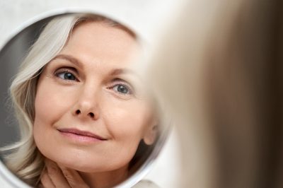 woman looking in the mirror at her skin