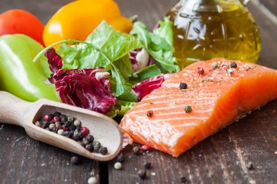 salmon, vegetables, and olive oil on wooden backdrop