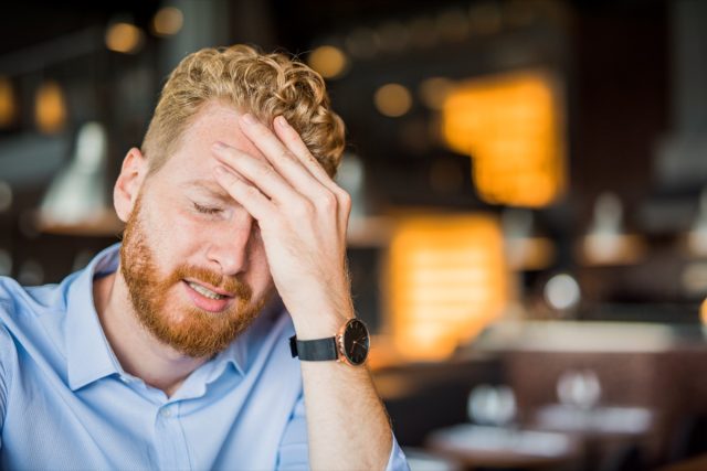 Bearded man touching his forehead.