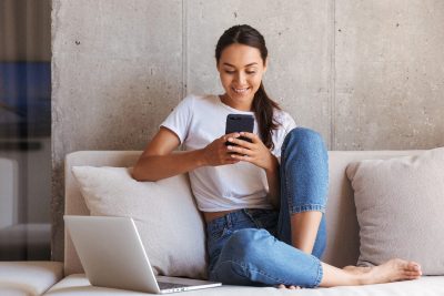 woman playing a game on her cell while sitting on couch