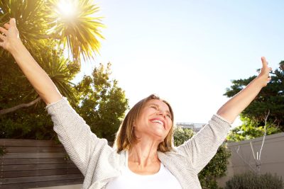 happy woman stretching arms in sunshine