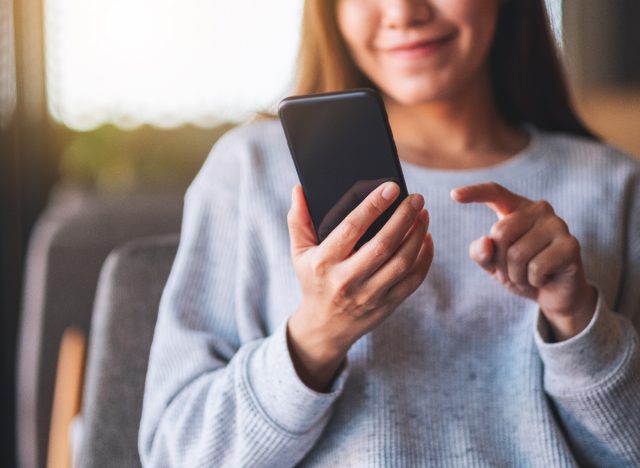 woman smiling in background while texting