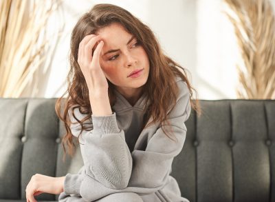 woman looking pensive sitting on gray couch