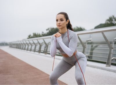 focused woman doing squats with resistance band outdoors