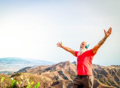 happy active senior man on top of mountain