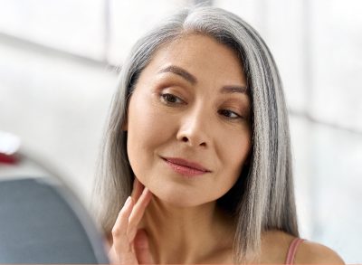 mature woman admires her glowing skin in mirror