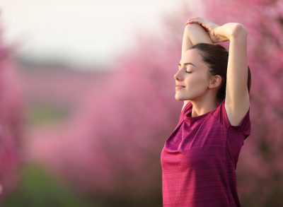 woman in pink shirt is relaxed as she stretches outside