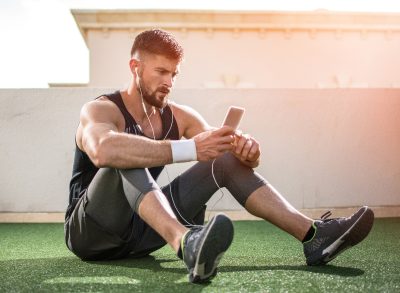 man taking test on phone sitting on turf