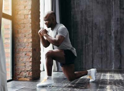 man performing backwards lunge in hotel room