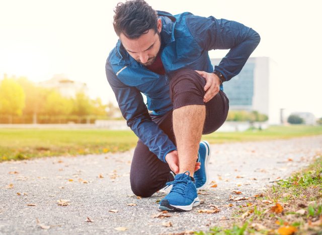 man kneeling down tending to tight muscles mid-run