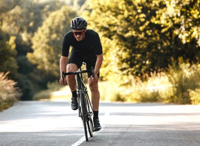 man bikes uphill on sunny day