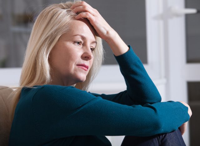 woman sits on the couch, tired, while dealing with menopause